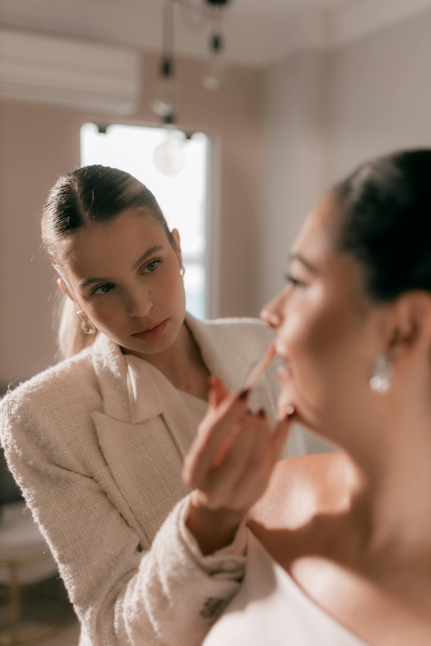 Close-up of a makeup artist meticulously applying lipstick to a bride before her wedding ceremony.